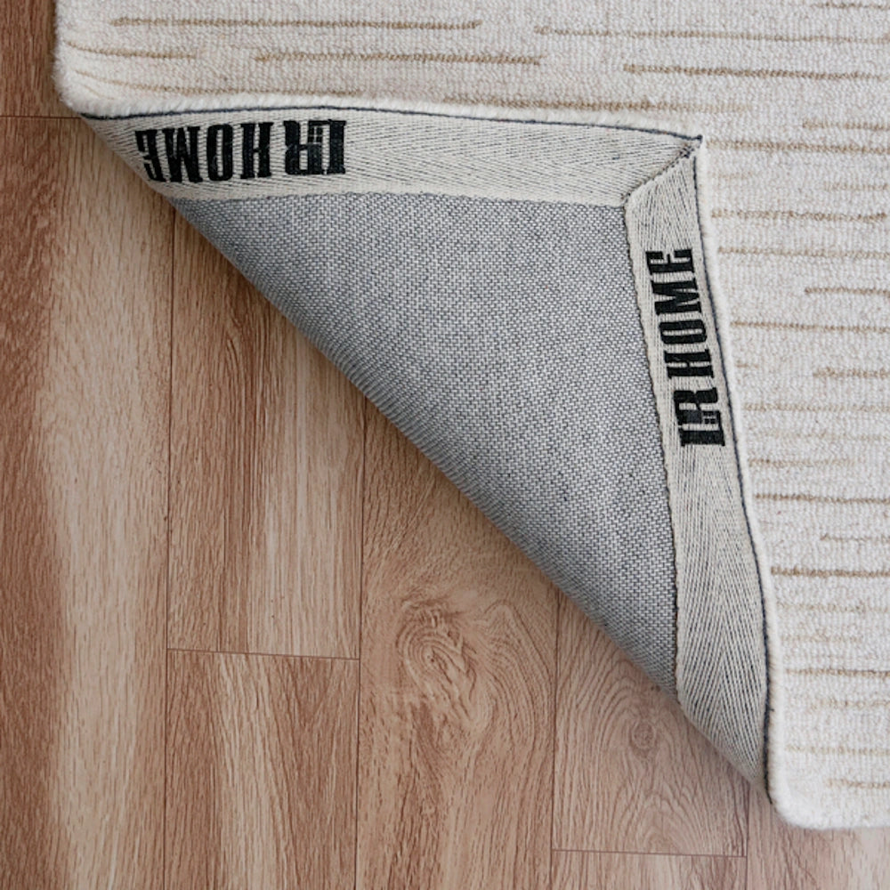 Backing of a hand-tufted rectangle Babylon rug with IR Home branding on a wooden floor.