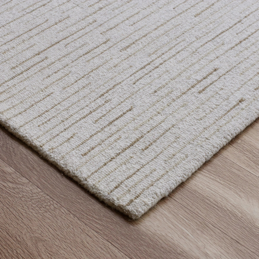 Close-up of a hand-tufted Babylon cream area rug showing textured lines on hardwood flooring.