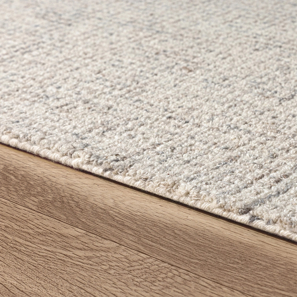 Modern neutral textured wool area rug with grey pattern on light oak hardwood floor.