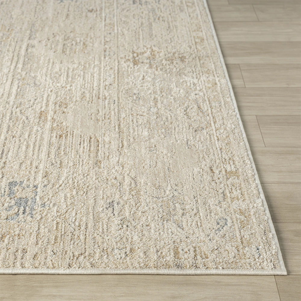 Beige distressed rectangle rug with a hand-tufted texture on a light wood floor. Monaco collection area rug.