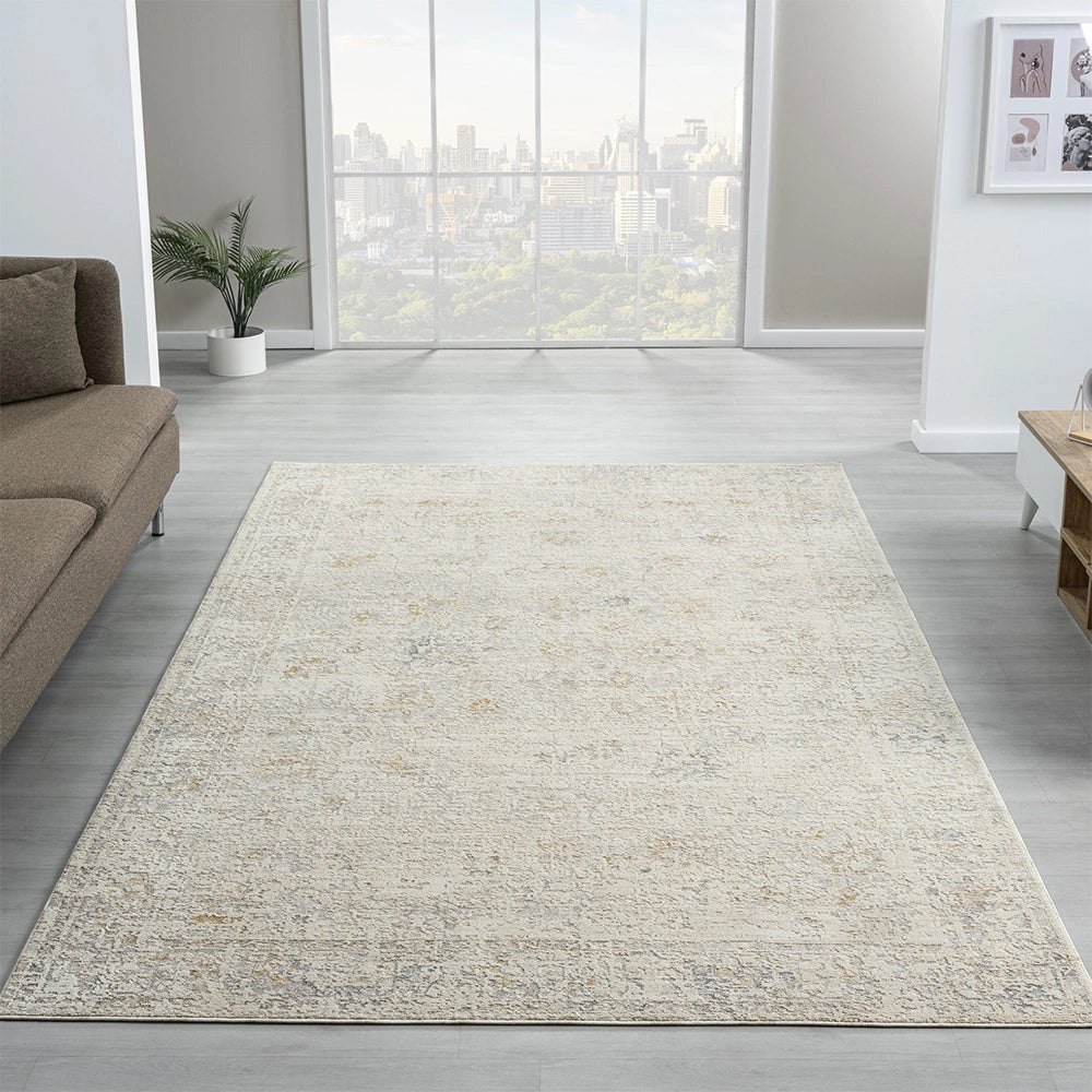 A contemporary living room featuring a vintage distressed beige and grey area rug, a sectional sofa, and a city skyline view.