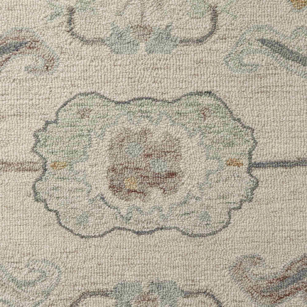 Detailed texture of a traditional beige area rug with green and blue floral motifs.