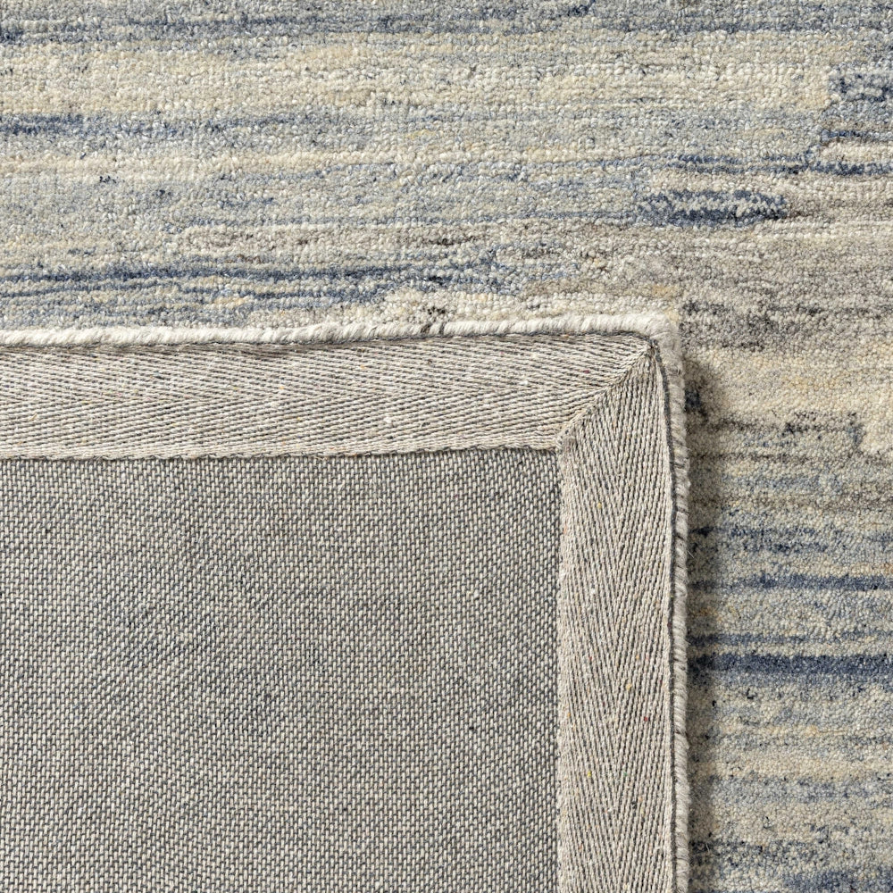 Close up of blue and ivory hand tufted rug backing showing durable woven underside and bound edge finish.