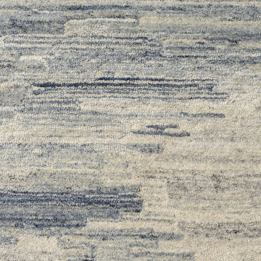 Close up of blue and ivory hand tufted rug with abstract striated pattern and soft textured pile detail.