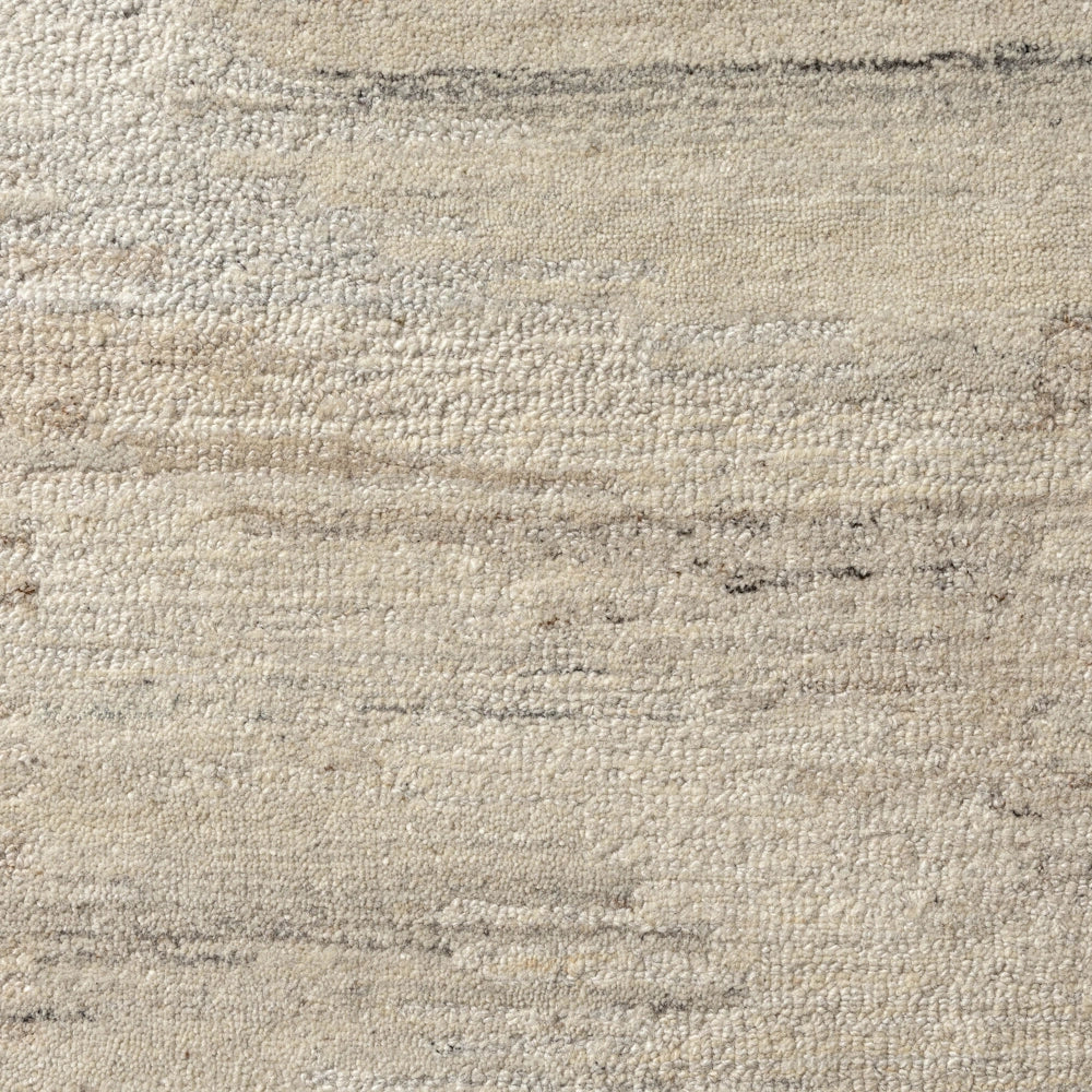 Close up of cream hand tufted rug with subtle striated pattern, textured pile and soft neutral tones.
