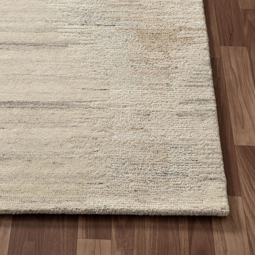 Close up of cream hand tufted rug corner with subtle striated pattern, textured pile and bound edges.