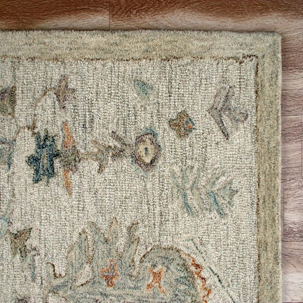 Hand-tufted rectangle vintage ivory rug with muted floral patterns on a wood floor.