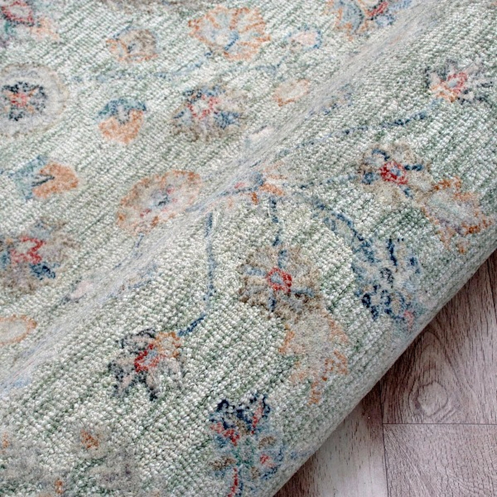Close-up of a hand-tufted rectangle vintage sage rug with detailed wool texture and floral patterns.