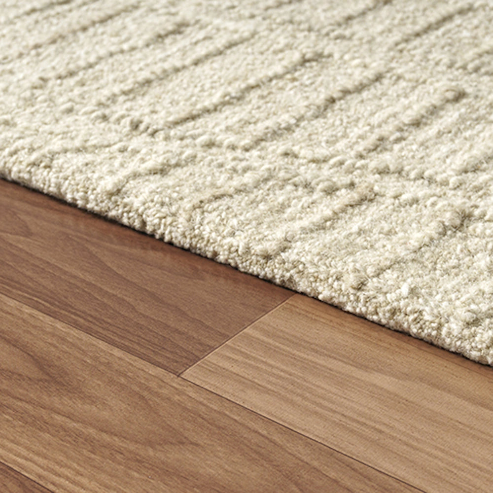 Hand-tufted cream rectangle haze area rug on a brown hardwood floor.
