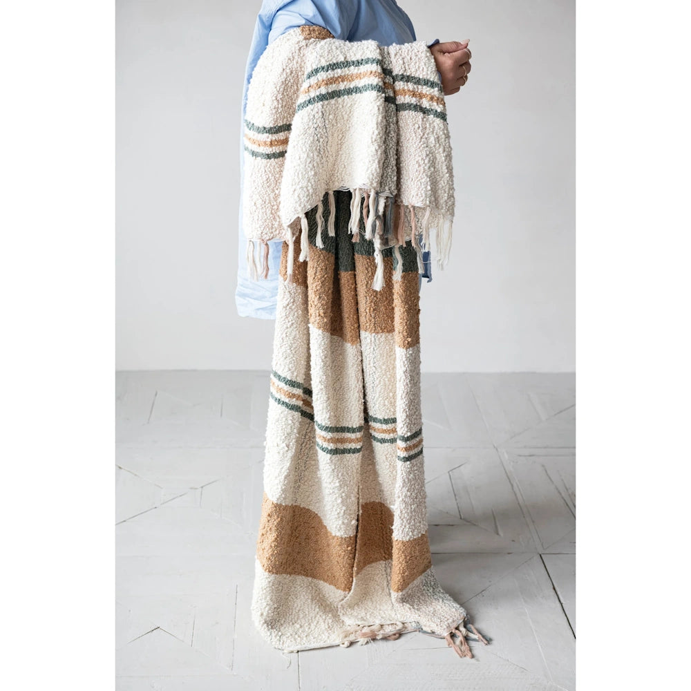 Lifestyle view of a person holding a multi-colored hand-woven cotton throw blanket with a plaid pattern and fringe.