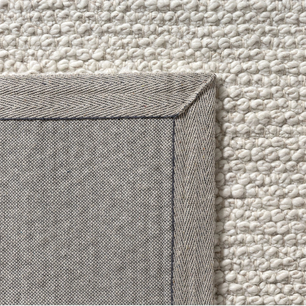 Close up of backing and corner binding on an ivory hand woven rectangle dome rug.