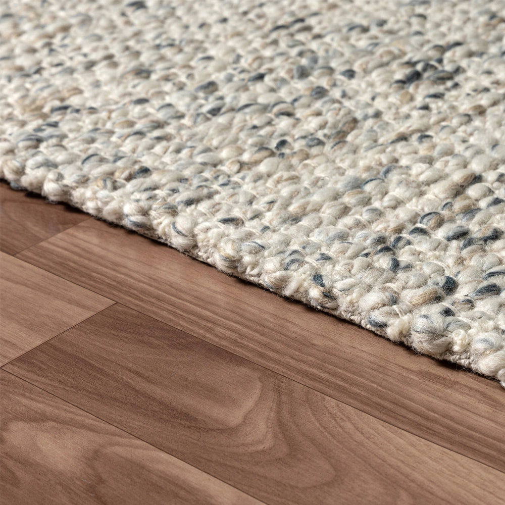 Hand-woven rectangle dome rug in ivory and grey textured wool on hardwood floor.
