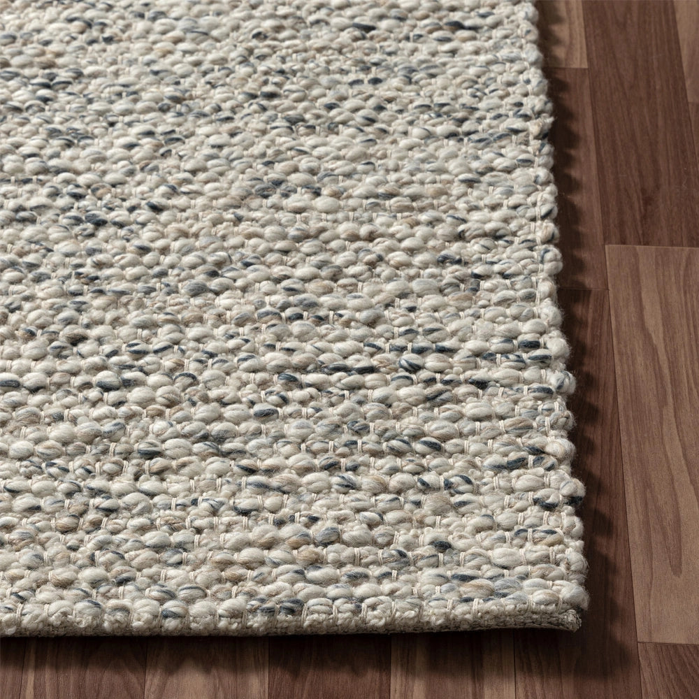 Hand-woven rectangle dome rug in ivory with textured wool on wood floor.