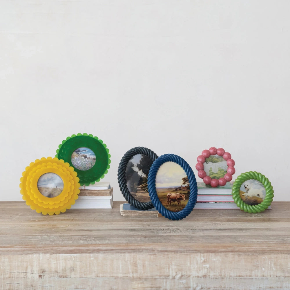 Six colorful, handmade resin picture frames in scalloped and rope textures displayed on a wooden surface with a white wall.