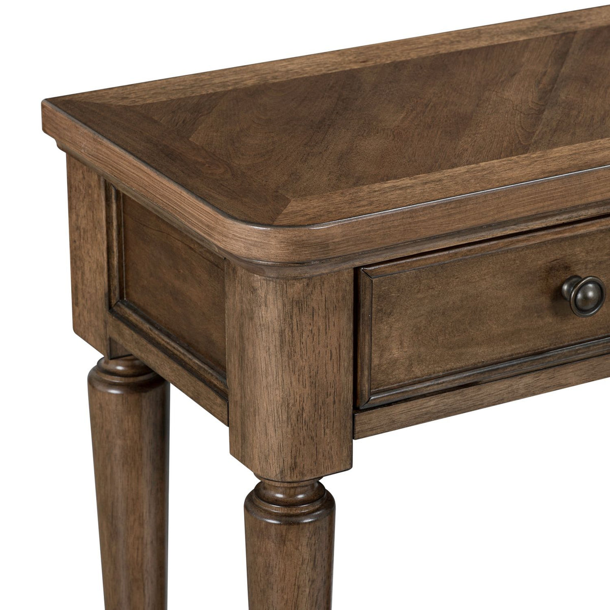 Close-up of a wooden console table corner with a chevron pattern top, molded drawer, and turned legs.
