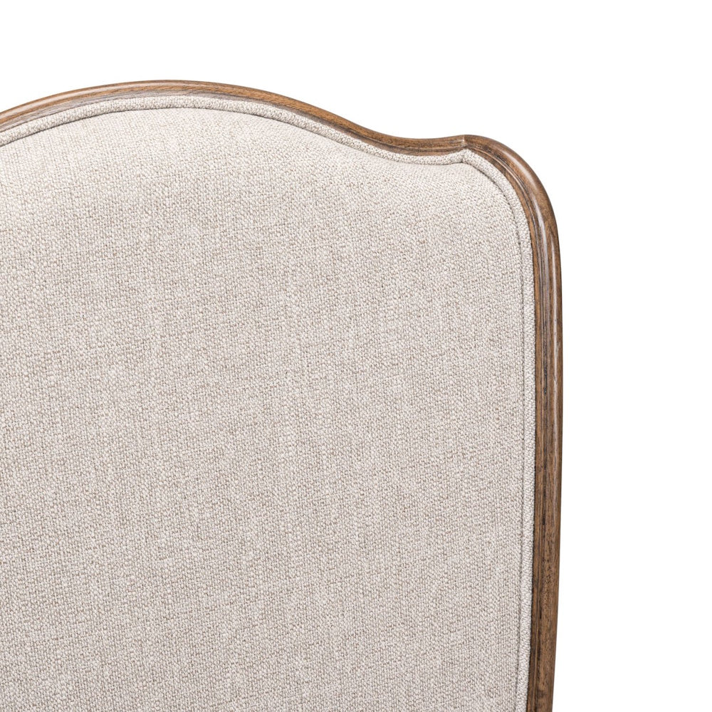 Close-up of a Harrison Heights upholstered side chair featuring beige textured fabric and a curved wooden frame.