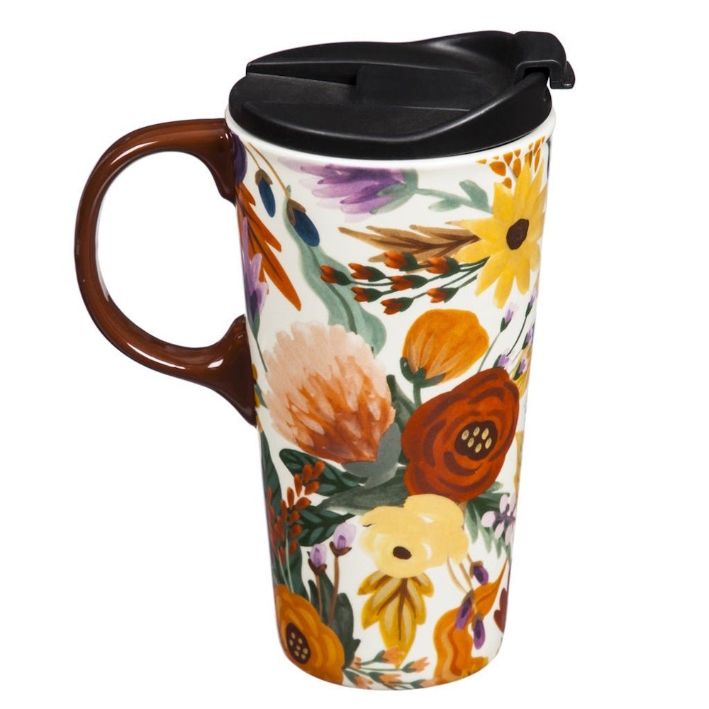 A tall ceramic travel mug decorated with a colorful fall floral pattern, featuring a brown handle and black lid.