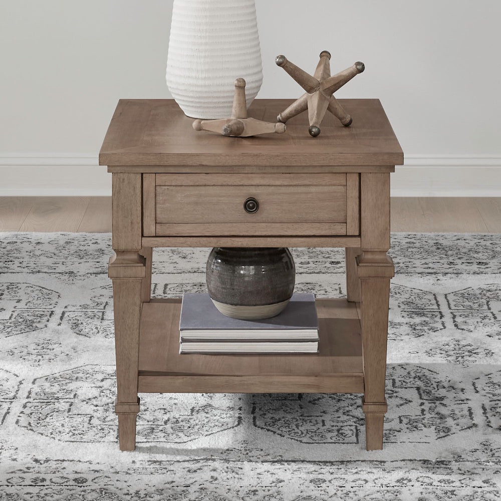Wood end table with drawer and lower shelf styled with decor in a cozy living room setting.