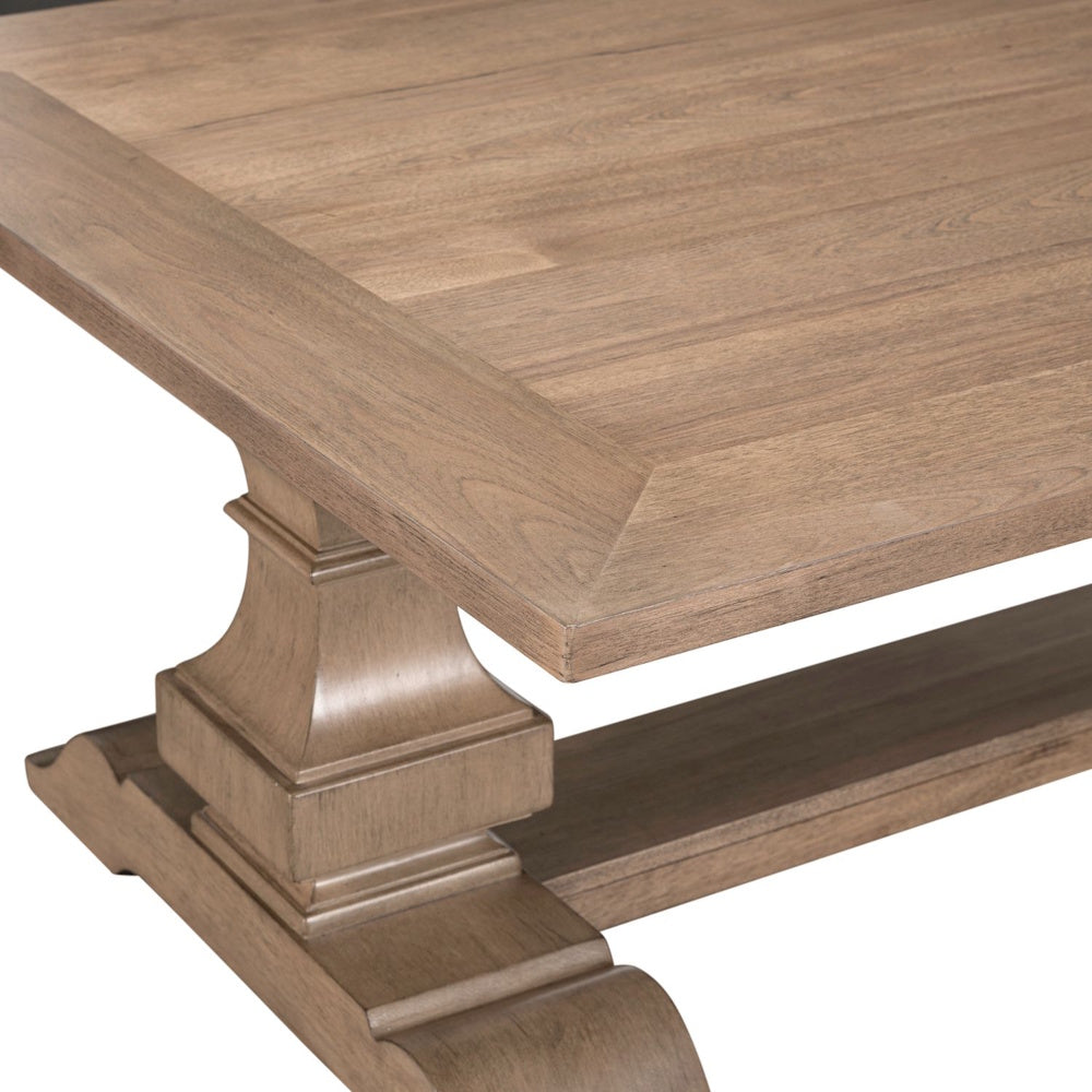 Close-up of wood cocktail table corner with natural grain top and carved pedestal base.