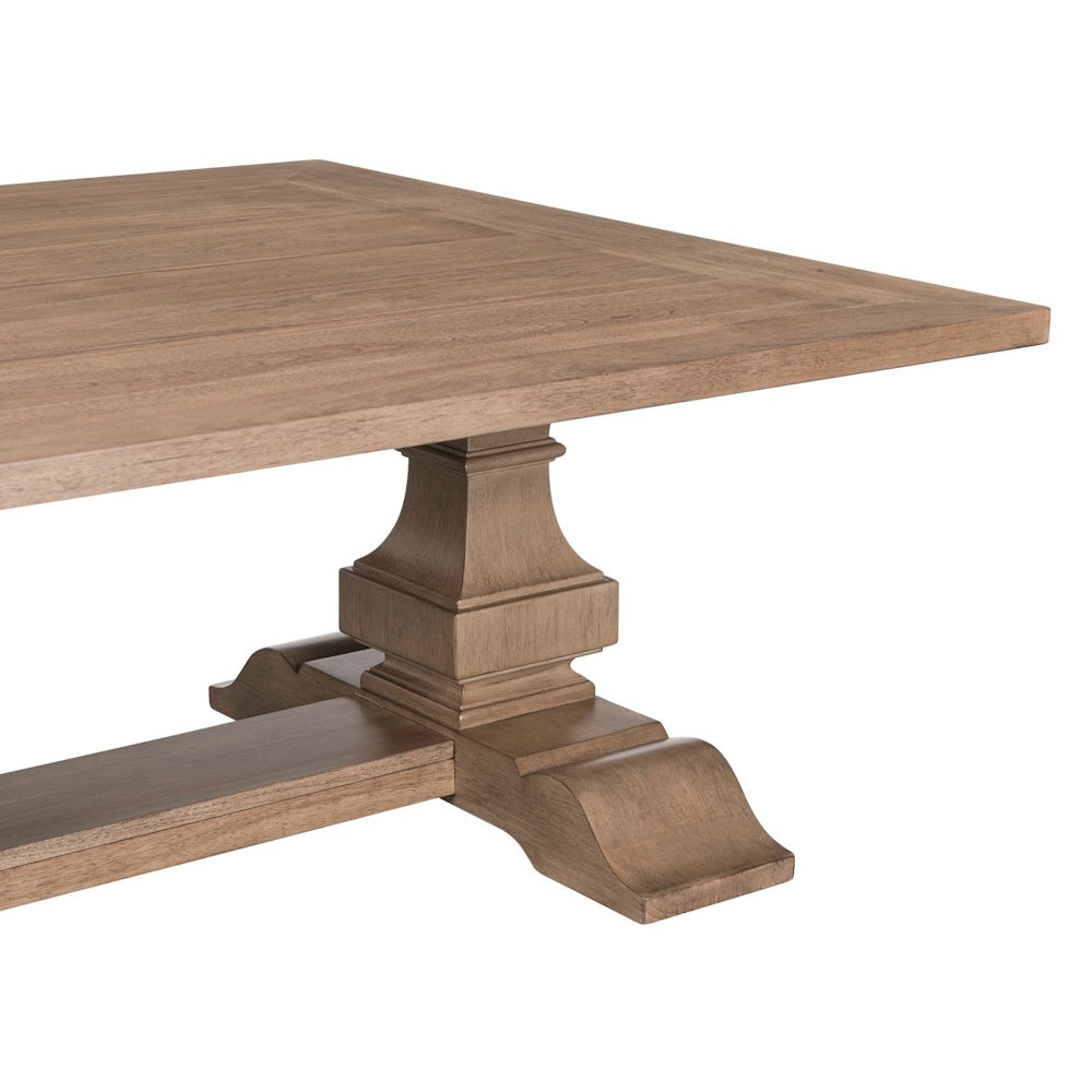 Close-up of rectangular wood cocktail table with carved pedestal base and natural grain top.