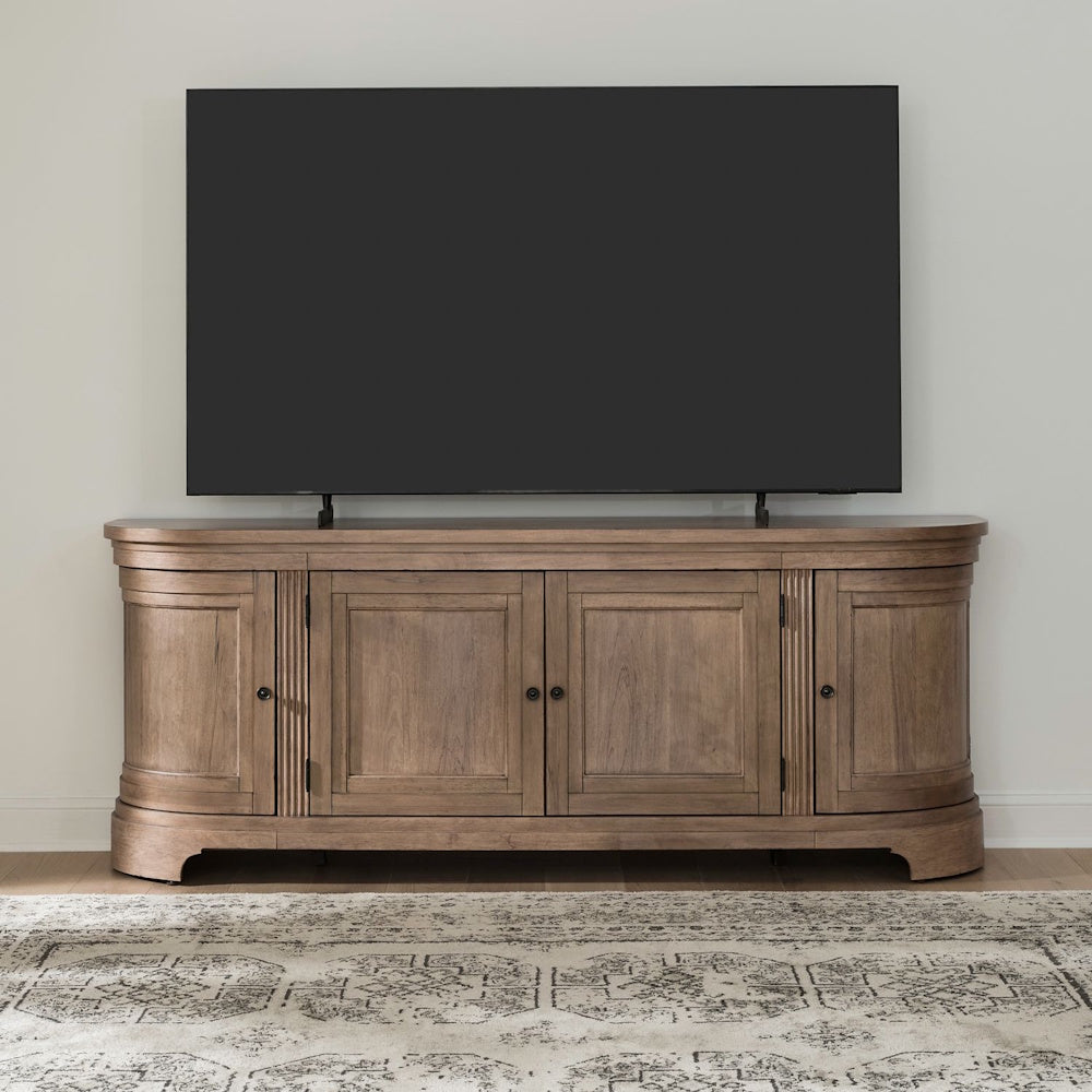 Curved wood TV console with four doors supporting a large flat-screen television on a patterned rug.