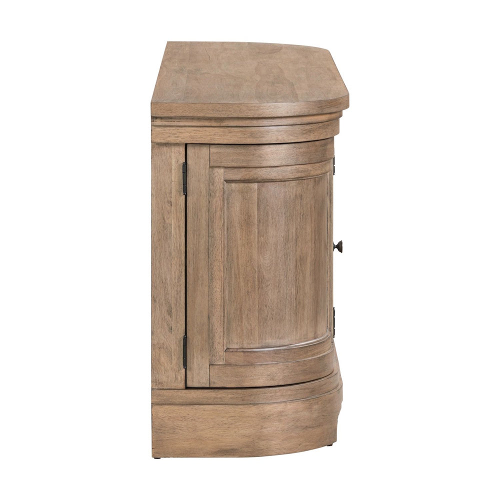 Side view of a light wood TV console with a curved front, paneled cabinet door, and rustic finish.