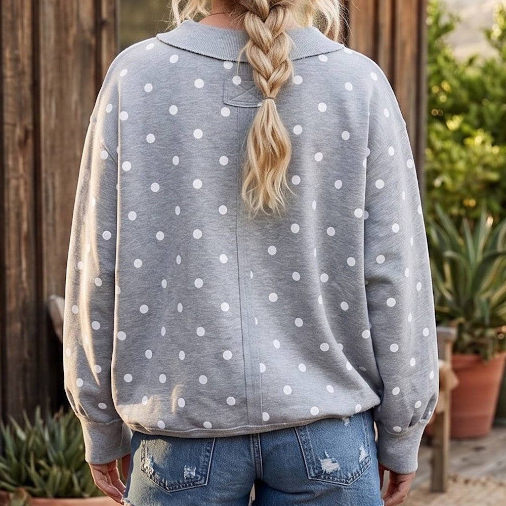 Back view of a person wearing an oversized heather grey pullover with a white polka dot pattern.