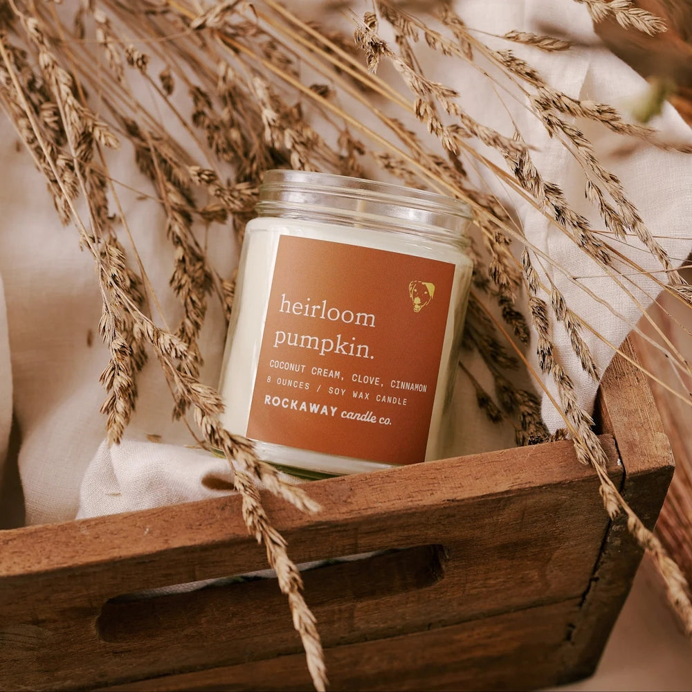 Rockaway Candle Co. Heirloom Pumpkin 8 oz soy wax candle inside a wooden crate with dried wheat grass stems.