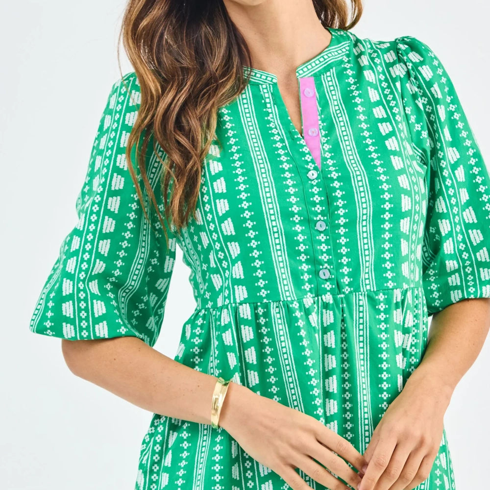 Green and white geometric print Riley dress with puff sleeves, a button-down bodice, and pink trim.
