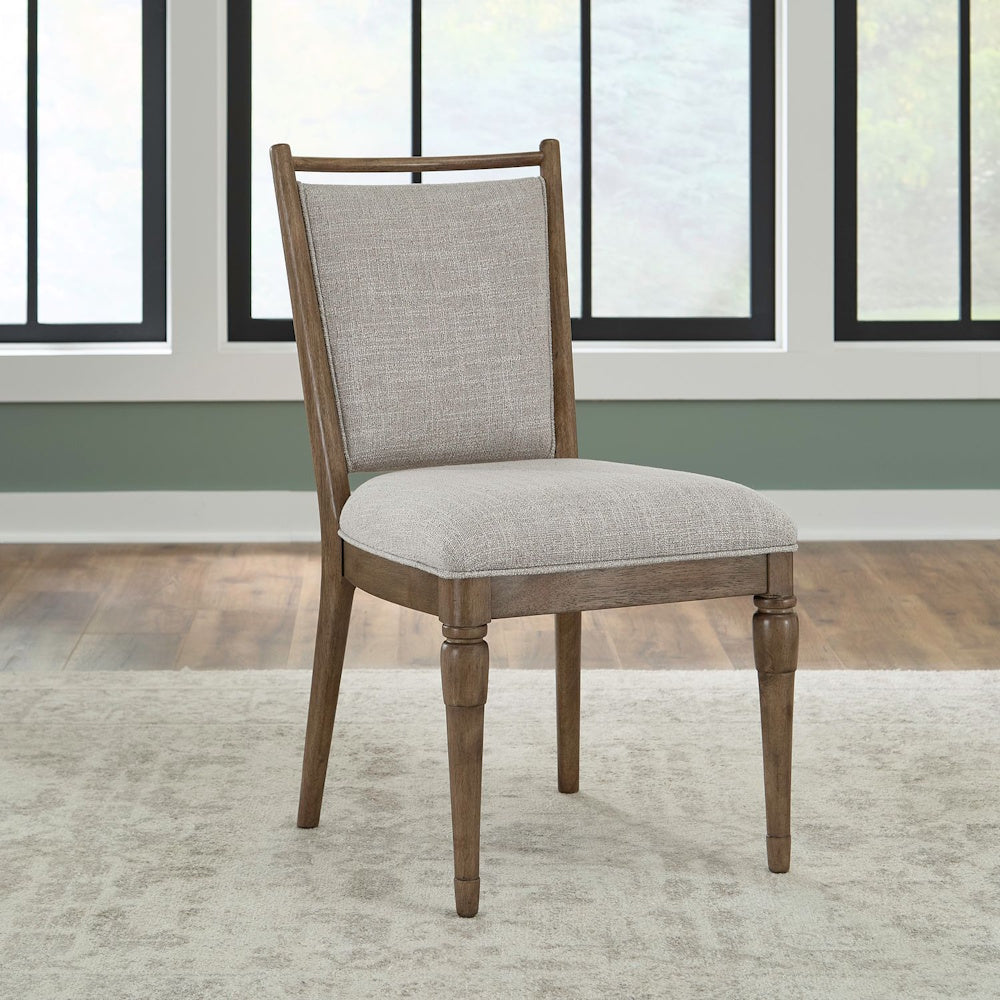 Upholstered dining chair with a light gray fabric seat and brown wood frame on an area rug.
