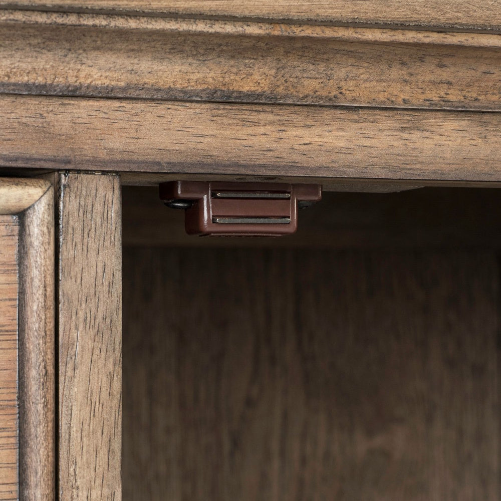 Close-up of a brown magnetic door catch latch installed inside a rustic wood sideboard cabinet.