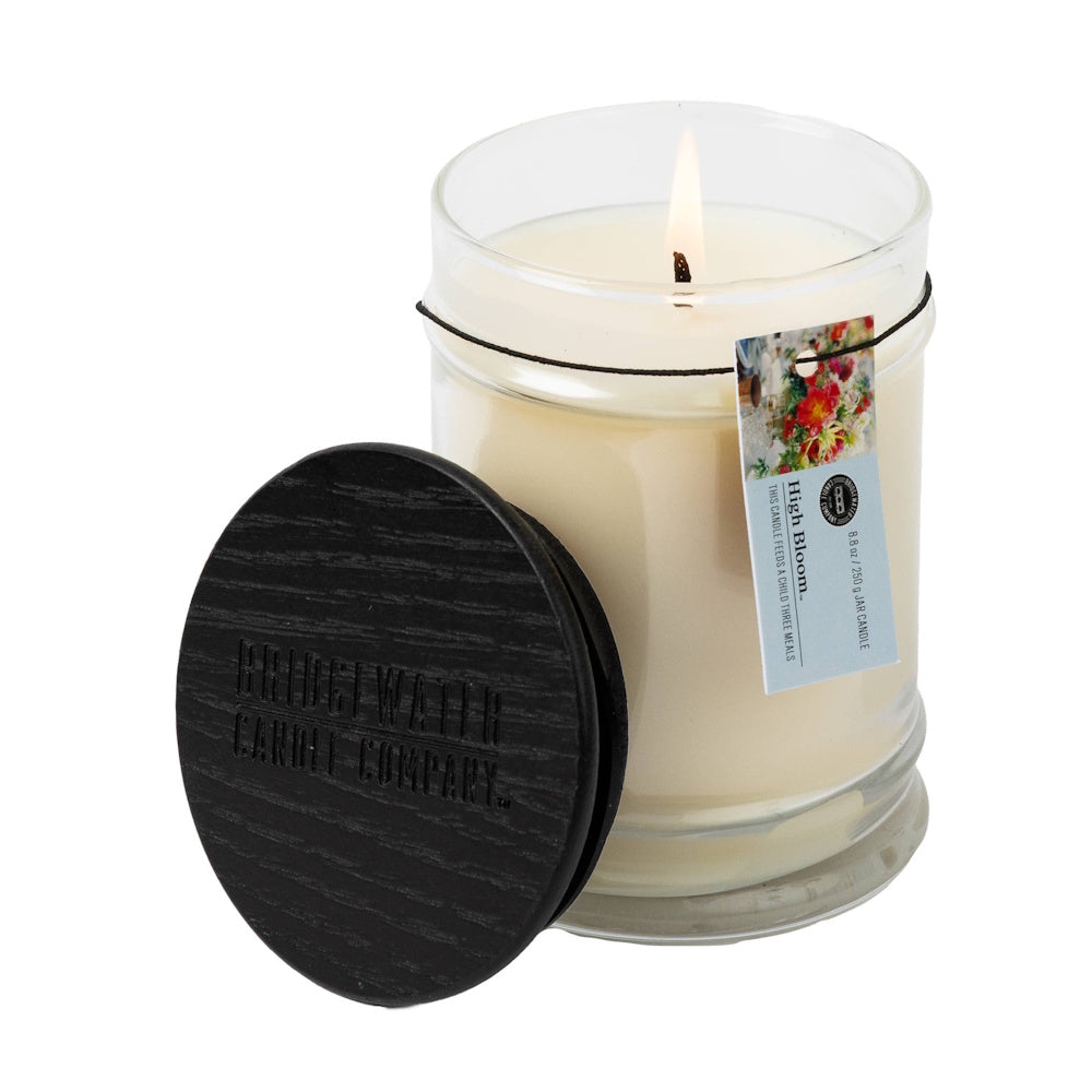 Bridgewater Candle Company High Bloom 8.8 oz jar candle with a lit wick and a black wooden lid on a white background.