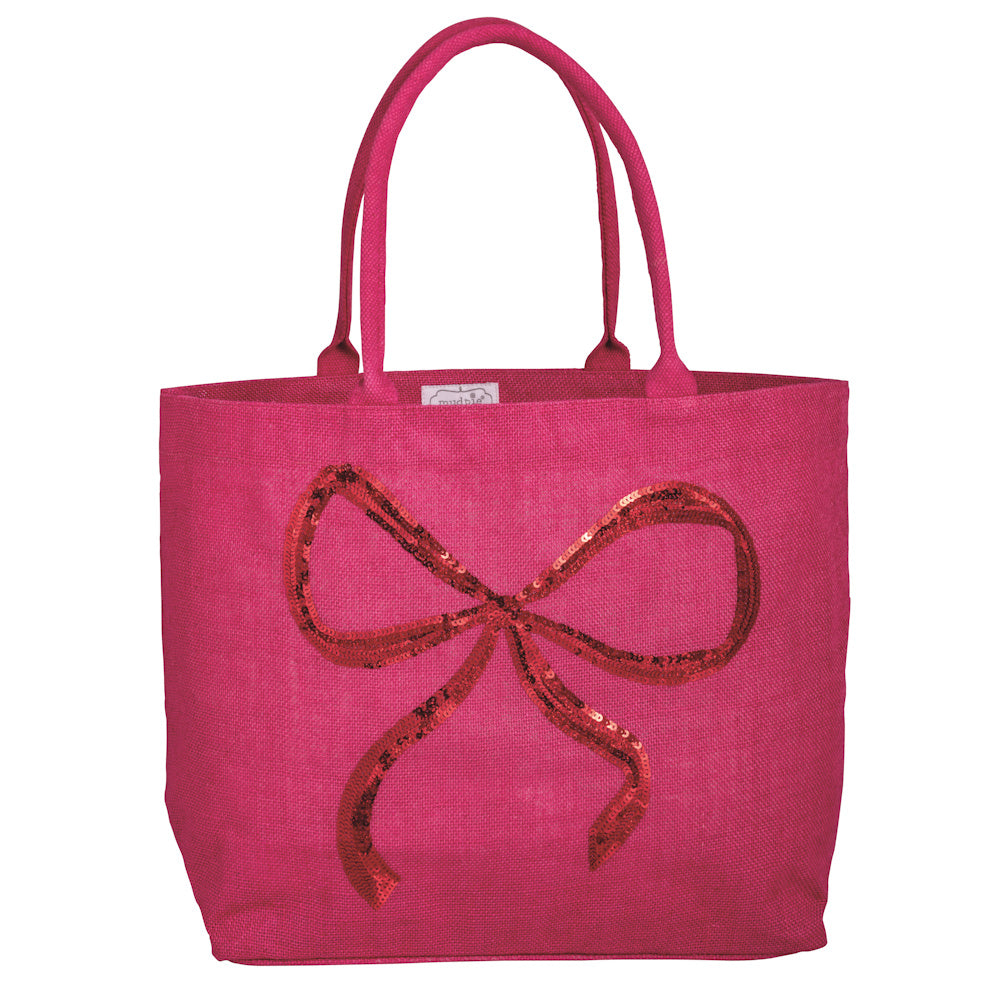 Hot pink jute tote bag with a sparkly red sequin bow design and matching shoulder straps for festive holiday style.