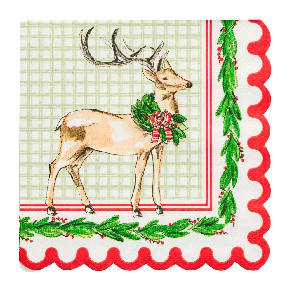 Flat lay of a white paper cocktail napkin with a holiday deer, green plaid, and red holly border.