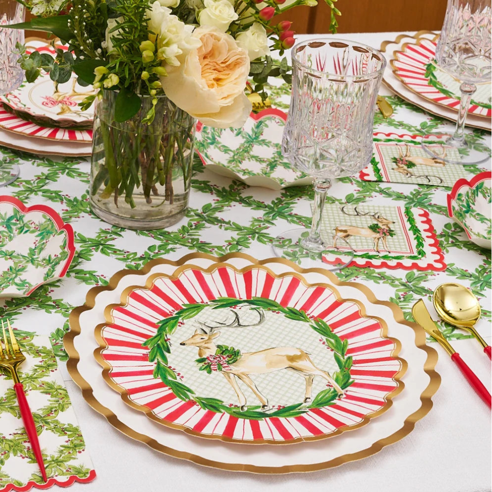 Front view of a holiday table setting with red, white, and gold paper dinner plates and a deer design.