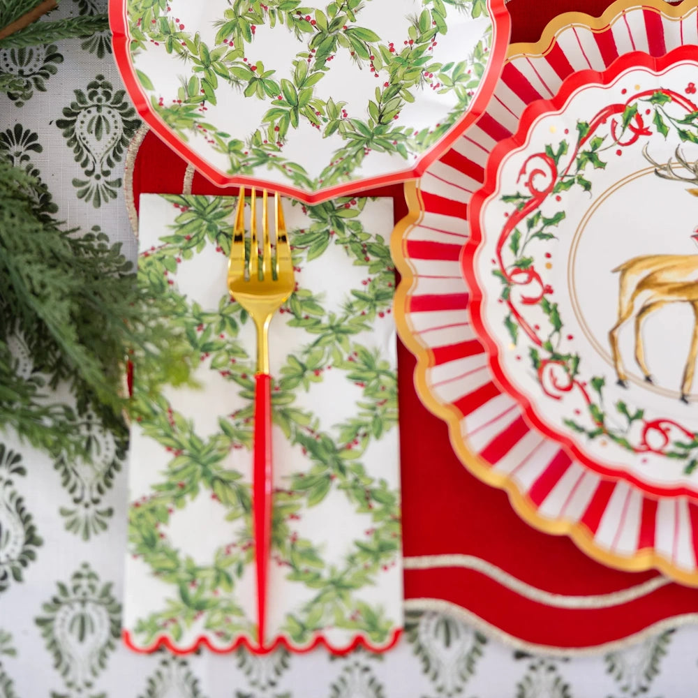 Overhead flat lay of a white paper Holly Berry guest towel styled on a festive holiday table setting.