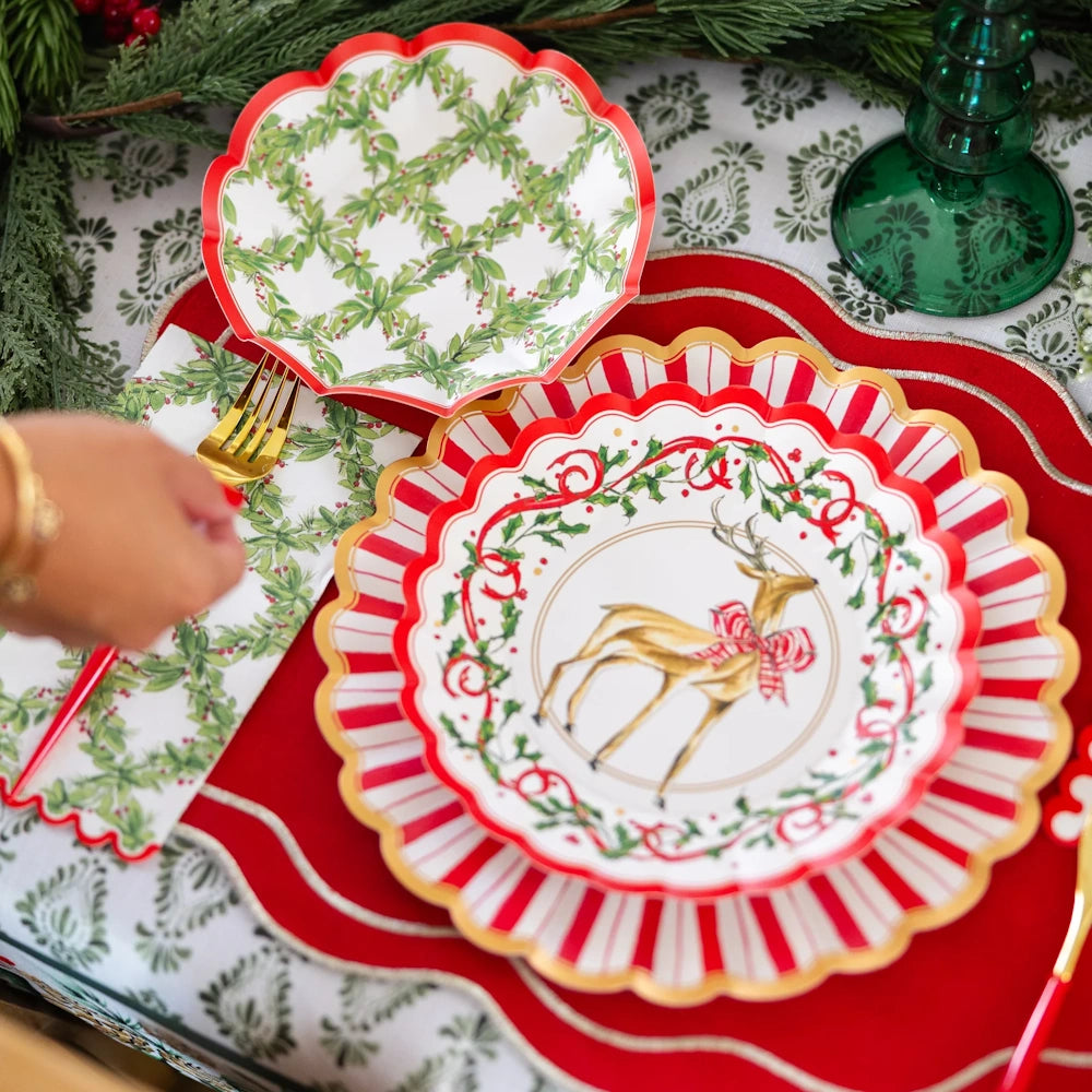 Overhead flat lay of a white paper Holly Berry guest towel styled on a festive holiday table.