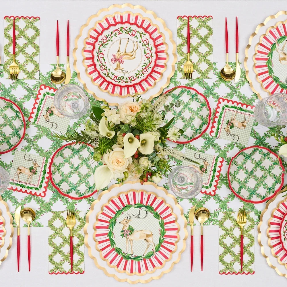 Overhead flat lay of white paper Holly Berry guest towels styled on a festive holiday table.
