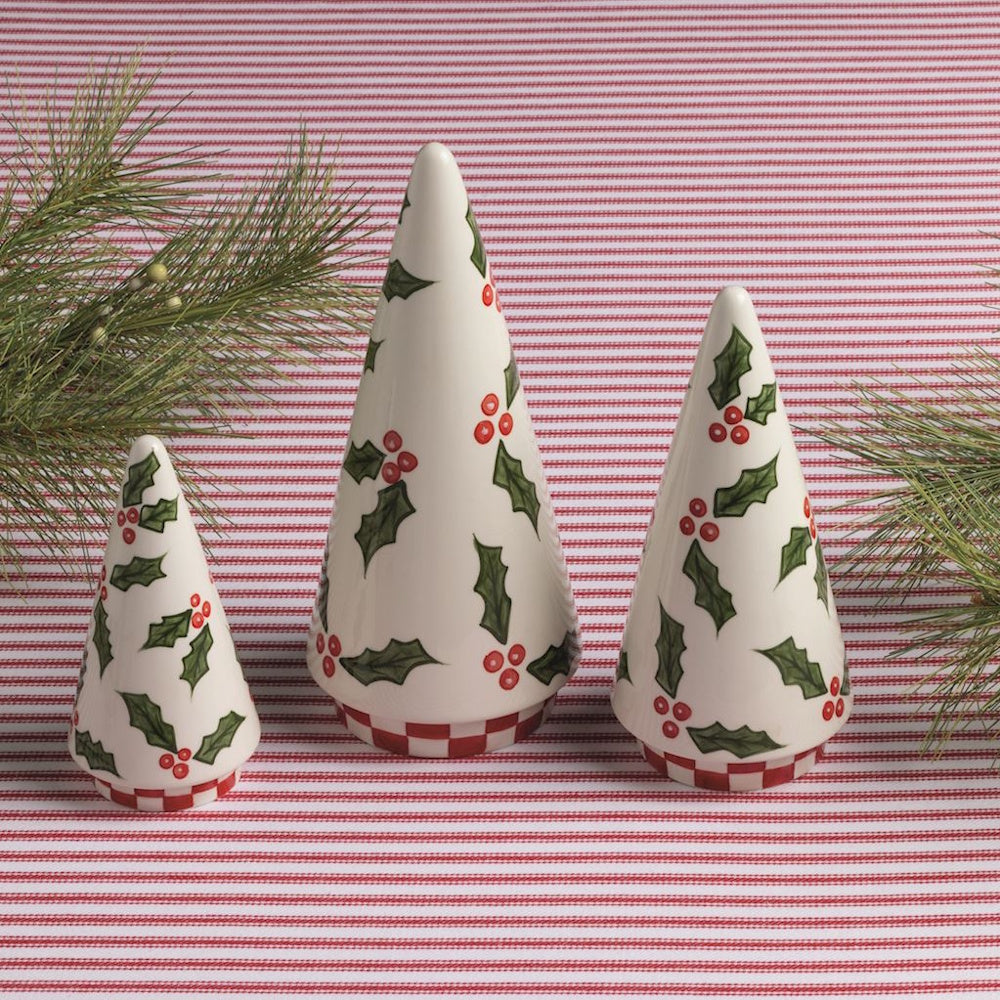 Three white ceramic cone Christmas trees painted with holly leaves, berries, and checkered bases.