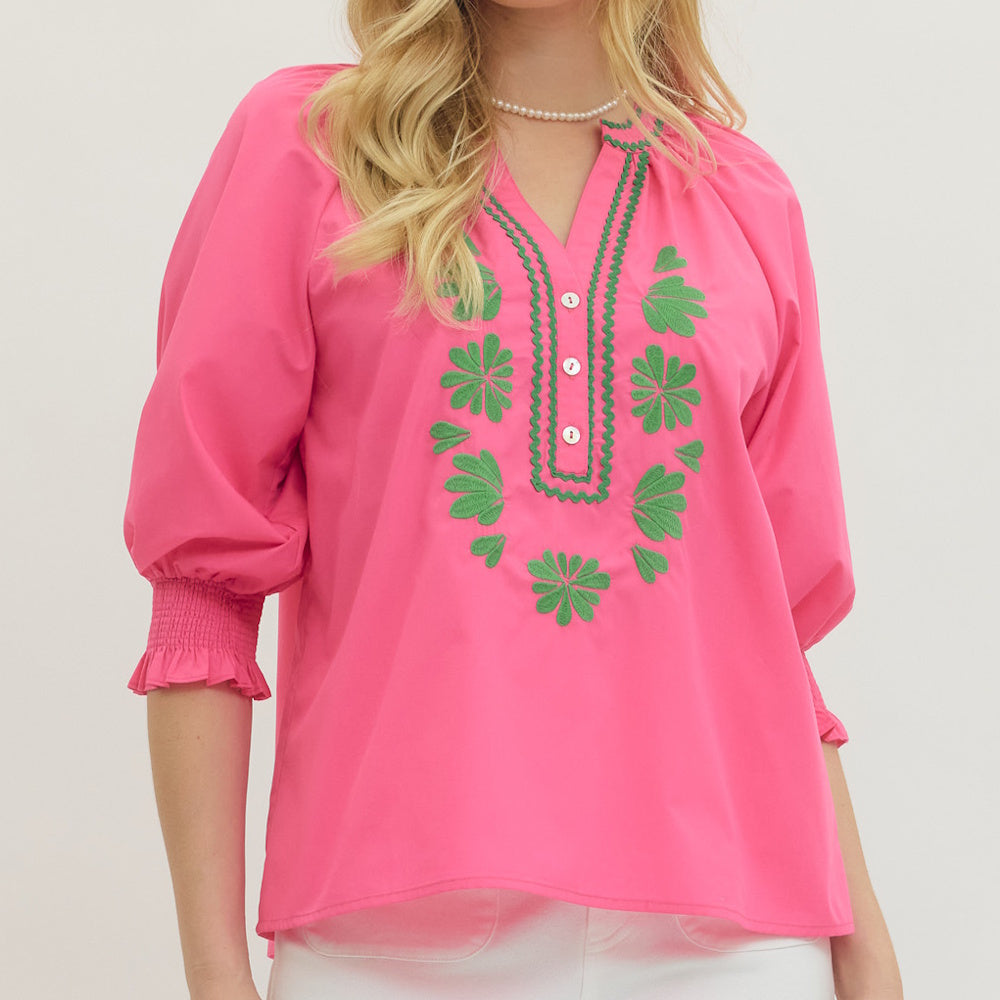 Hot pink blouse with green floral embroidery, split neckline, puff sleeves and smocked cuffs.