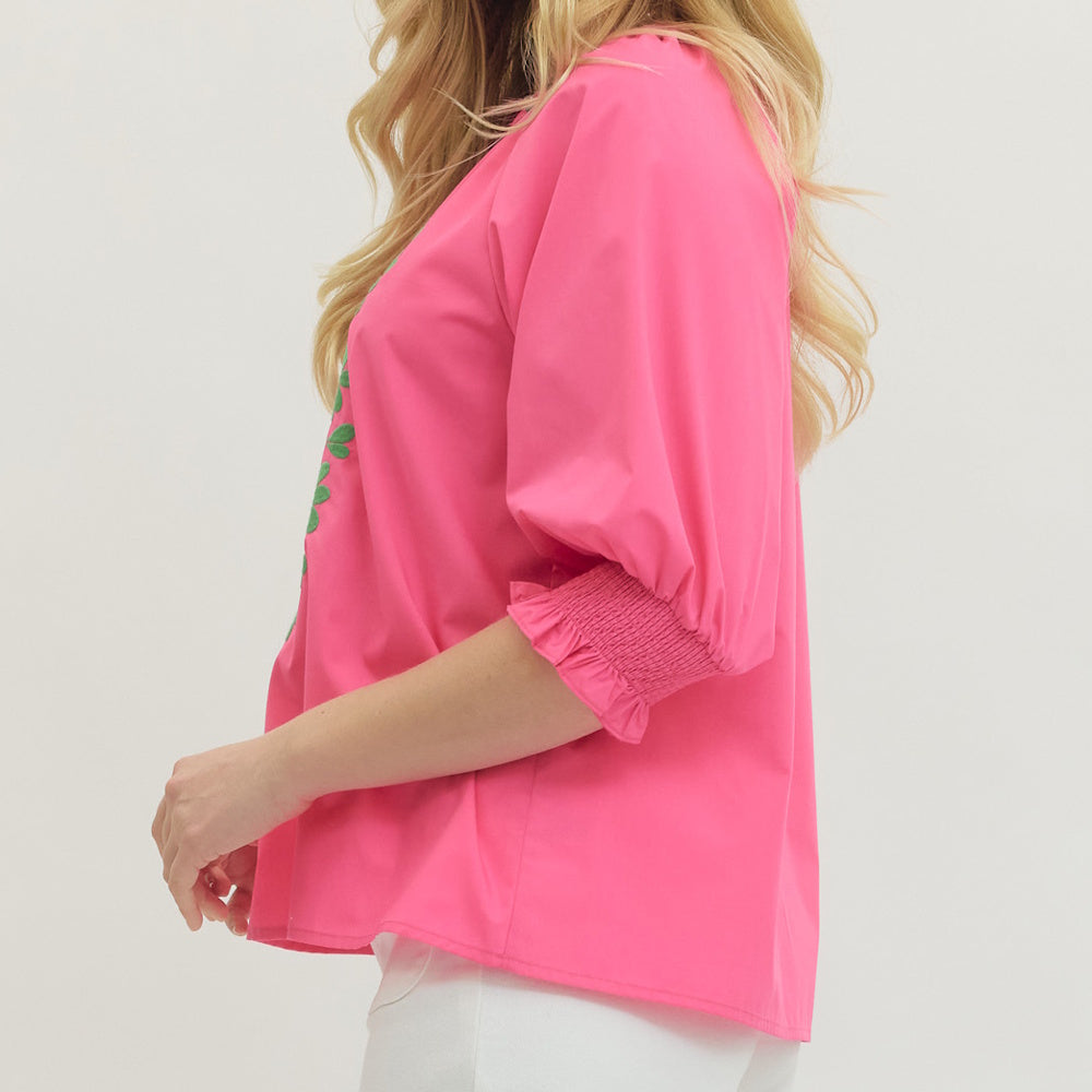 Side view of hot pink blouse with puff sleeve, smocked cuff and relaxed fit silhouette.