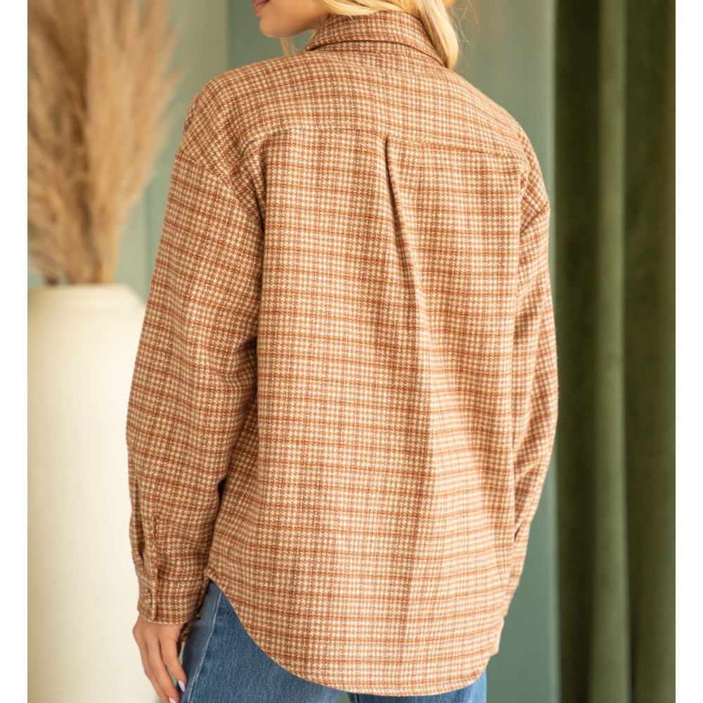Back view of a woman wearing a relaxed-fit brown houndstooth pattern shacket and blue jeans.