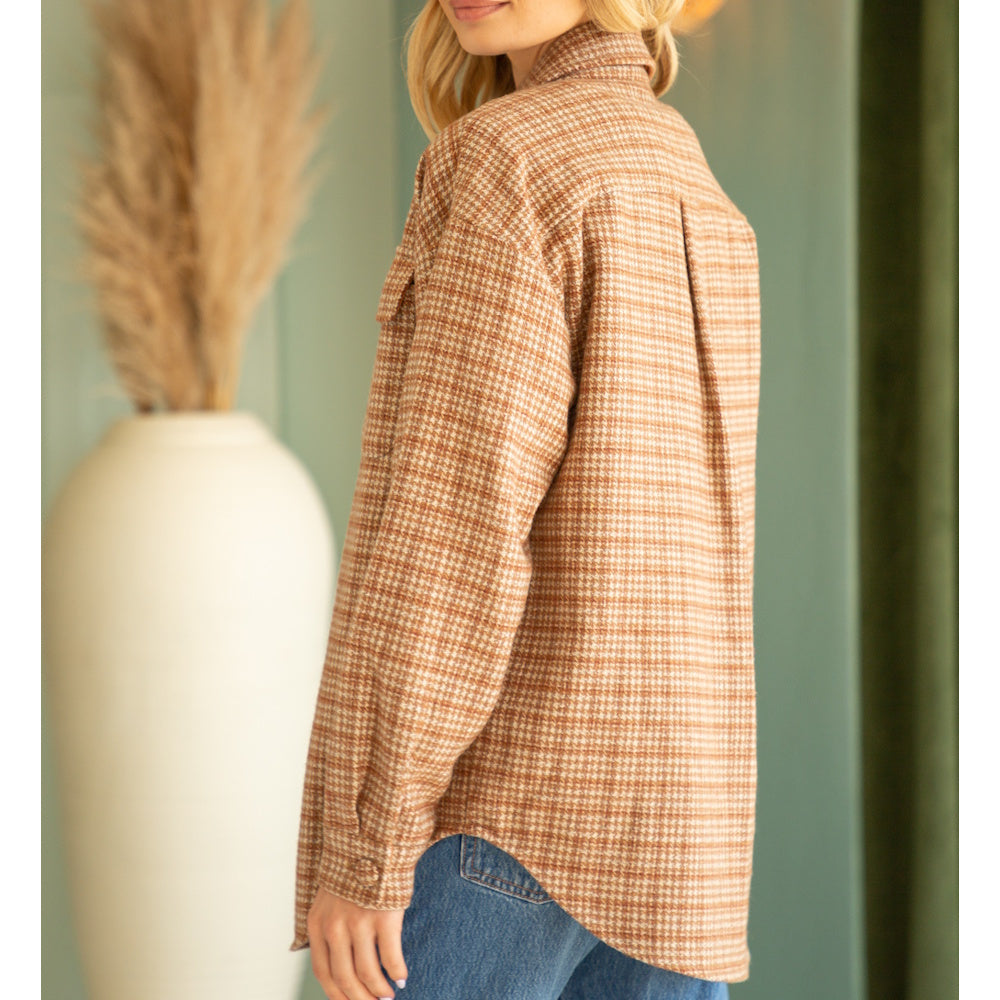 Side profile of a woman wearing a brown houndstooth pattern button-down shacket with blue jeans.