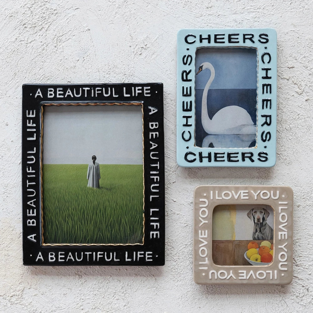 Three decorative stoneware photo frames with embossed text and gold-rimmed borders on a textured wall.