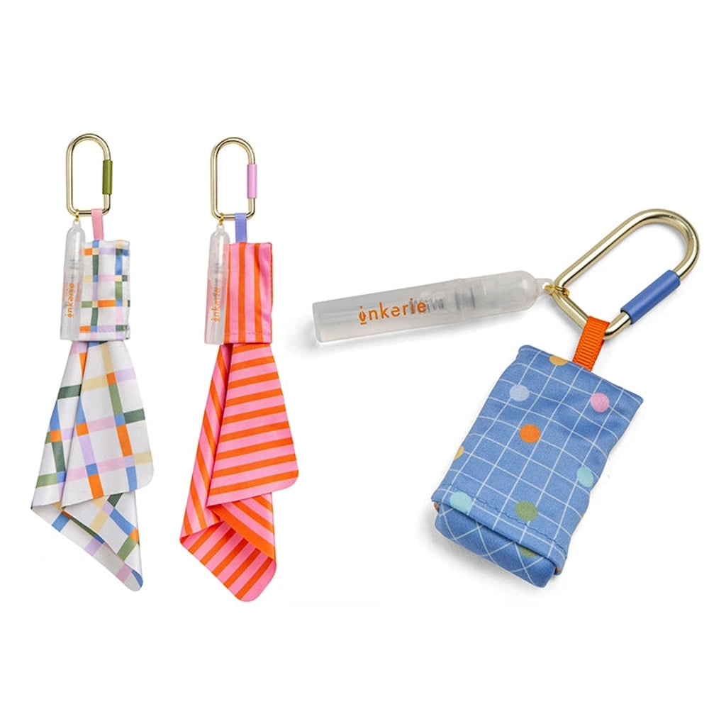 Inkerie on-the-go lens and screen cleaning kits featuring patterned microfiber cloths and spray bottles on carabiners.