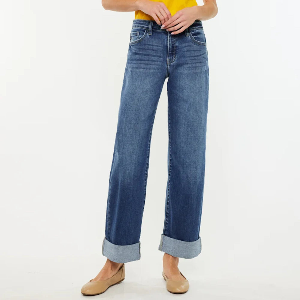 Woman wearing Ivanna Essentials high-rise wide-leg jeans in medium wash blue with cuffed hems and tan ballet flats.