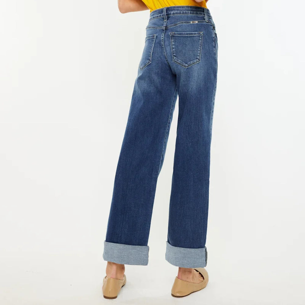 Back view of high-rise wide-leg jeans in dark wash denim with cuffed hems, paired with tan flats and a yellow top.