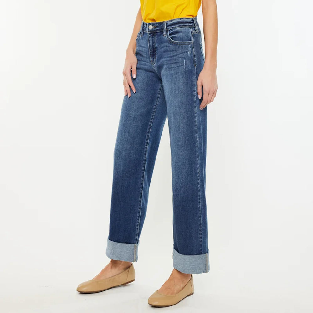 High-rise wide-leg blue jeans with cuffed hems, paired with tan ballet flats and a yellow top on a white background.