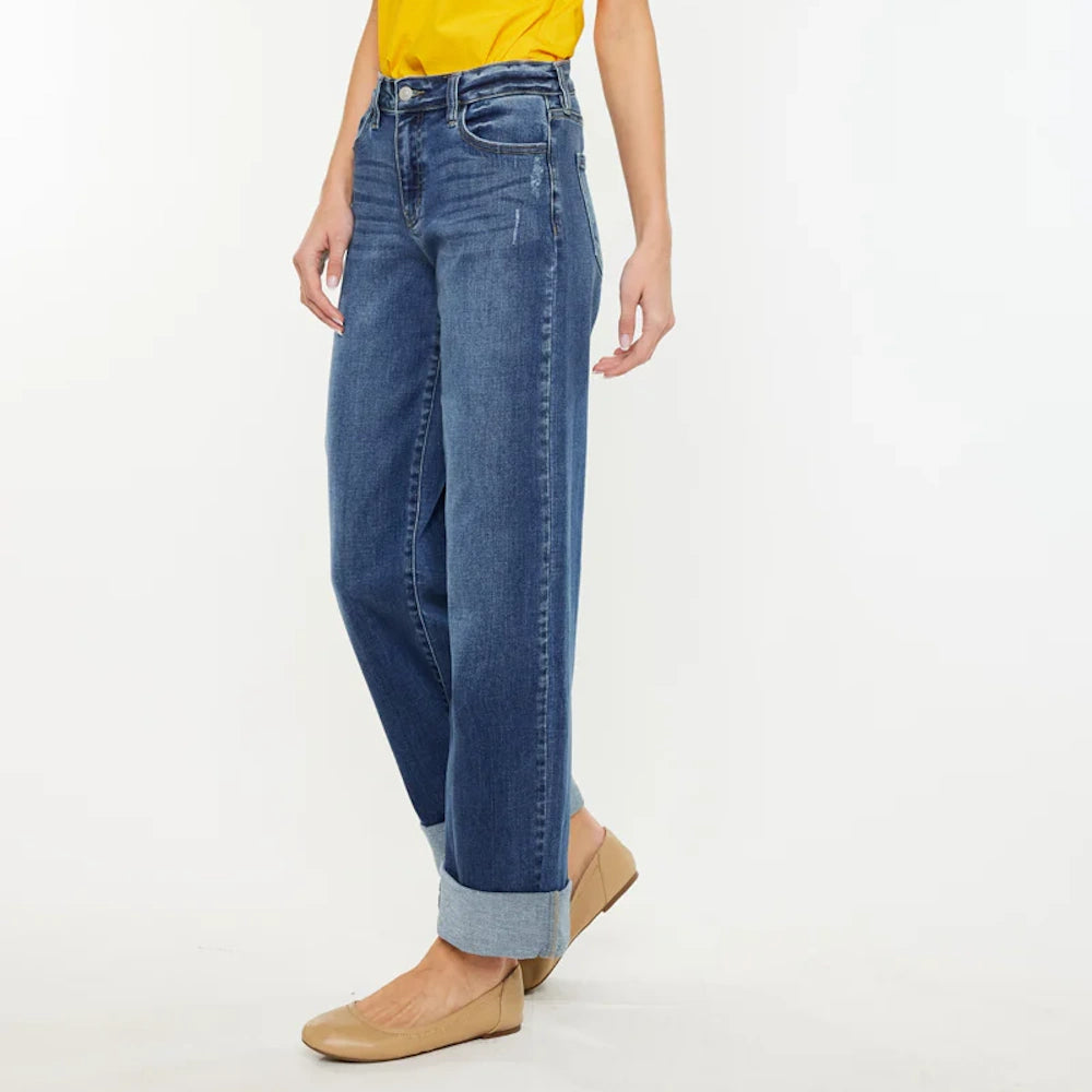 Woman wearing Ivanna Essentials high-rise wide-leg jeans in dark wash blue with cuffed hems and tan ballet flats.