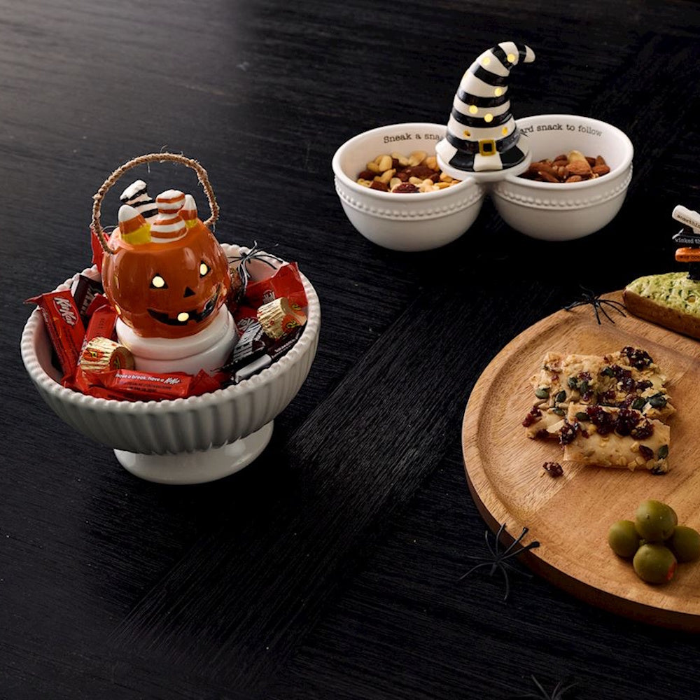 Light-up jack-o'-lantern basket sitter in a Halloween candy bowl on a dark table.
